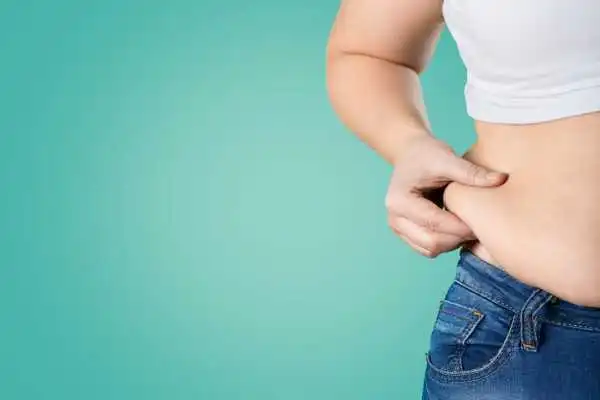 Image of woman pinching her love handles to show weight gain Gloucestershire